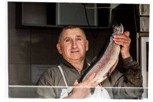 Man at farmers market stall holding a fresh fish