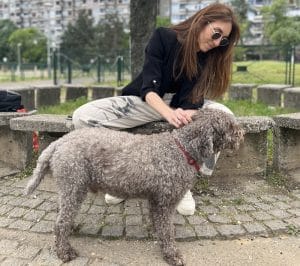 Young woman stroking a dog in a brutalist block